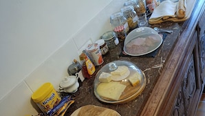 A kitchen counter with various food items, including jars of spices, a cutting board, a knife, and a bowl of cheese.