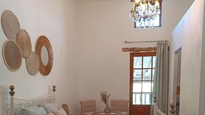 A bedroom with a bed, a chair, a small table, a lamp, and a window with curtains.