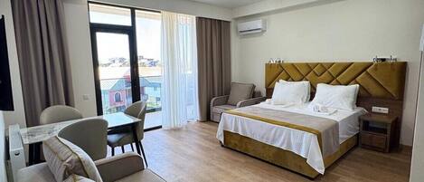A hotel room with a bed, a sofa, a desk, and a chair.