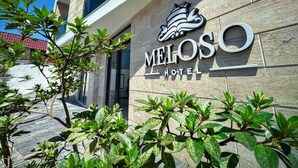 Het uiterlijk van Hotel Meloso, met een stenen gevel en een heldere lucht.