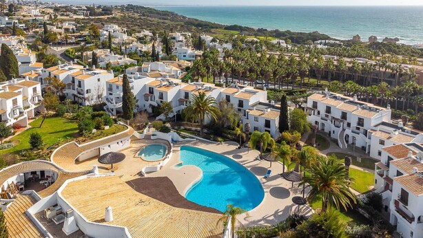 A resort with a large swimming pool, white buildings, and a view of the sea. - Apt. 77 - São Rafael by HelloVacations (Albufeira)