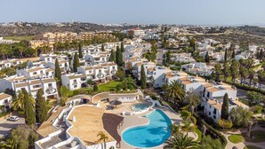 A residential area with a large swimming pool surrounded by white buildings and palm trees. - Apt. 77 - São Rafael by HelloVacations (Albufeira)