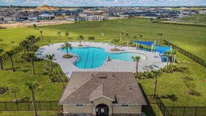 Un quartier résidentiel doté d’une piscine, entouré de palmiers et d’une pelouse bien entretenue.