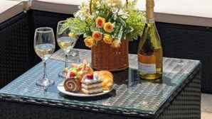 Un espace extérieur aménagé avec une table dressée pour un repas, comprenant une bouteille de vin, un panier de fleurs et un dessert.