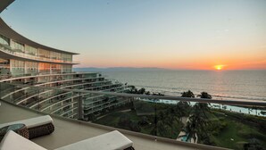 A modern hotel with a curved balcony overlooking a sunset view of the ocean. - Beachfront Apartment | 6 Bedrooms | Nuevo Vallarta Peninsula (Bucerías)