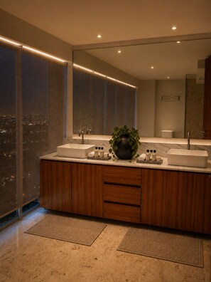 Un bany modern amb un mirall gran, dues dutxes i una planta en test amb el lavabo.