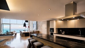 A modern kitchen with a large island, bar stools, and a view of the sea. - Beachfront Apartment | 6 Bedrooms | Nuevo Vallarta Peninsula (Bucerías)