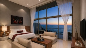 A modern hotel room with a large bed, a sofa, a coffee table, and a TV. - Beachfront Apartment | 6 Bedrooms | Nuevo Vallarta Peninsula (Bucerías)