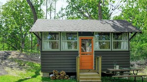 A small cabin with a wooden door, windows, and a picnic table. - Sun View - Antique Scout Cabin Suite (Troy)
