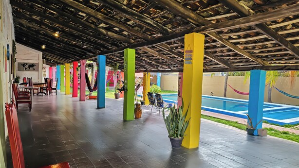 Un espacio exterior cubierto con pilares de colores, una piscina y zonas de estar.