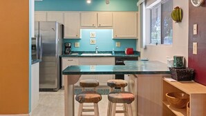 A kitchen with white cabinets, a stainless steel refrigerator, a sink, and a wooden bar stool area. - Pet-Friendly Sun City Retreat Near Golf & Shops (Sun City)
