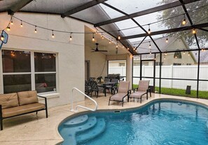 An outdoor pool area with a covered patio, string lights, and seating. - Chic 3 BR w/ Pool Near Disney Magic (Clermont)