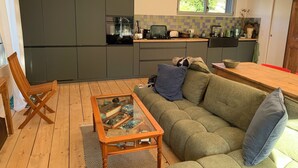 Eine moderne Küche mit grauen Schränken, einem Holzespeisetisch und einem grünen Sofa mit Kissen.