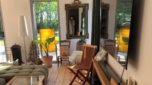 Ein Wohnzimmer mit Sofa, Sesseln, Couchtisch, Fernseher und einem großen Spiegel.