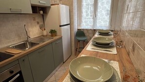 A narrow kitchen with a built-in oven, a sink, and a window with patterned curtains. - Domus Vittoria, the ideal apartment for your family in the Vatican area (Roma)