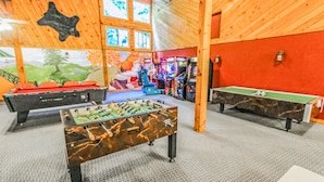 Un espacio recreativo interior con mesas de fútbol de mesa, billar y máquinas de videojuegos.