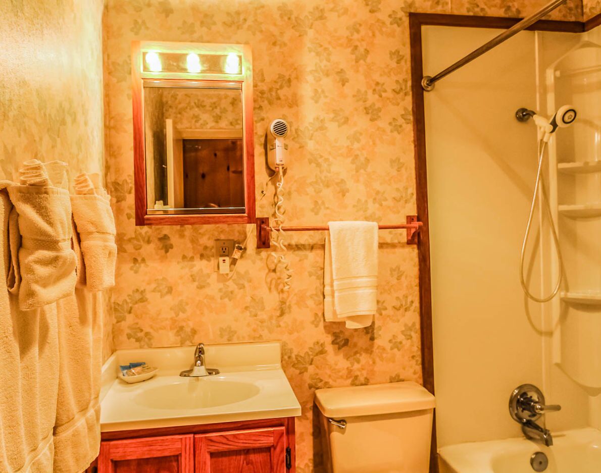 A bathroom with a sink, mirror, and shower.