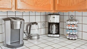 Una cocina con cafetera, hervidor y soporte para tazas.
