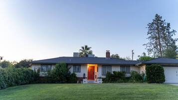 A single-story house with a front porch, a chimney, and a well-maintained lawn.