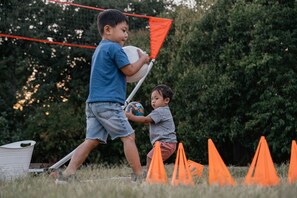 Two children playing with a ball and a kite in an outdoor setting with a net and orange cones. - The Songbird 99 | An Outdoorsy Escape For Families (Redding)
