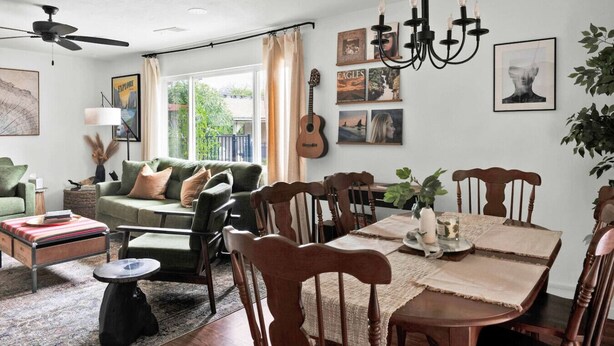 Un comedor con mesa de madera, sillas y una araña.