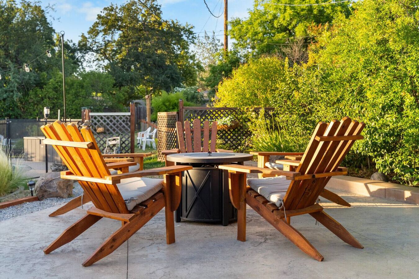 Eine Terrasse im Freien mit einem runden Tisch und zwei Adirondack-Stühlen.