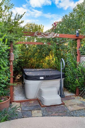 A hot tub under a wooden pergola in a garden. - The Songbird 99 | An Outdoorsy Escape For Families (Redding)