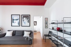 A modern living room with a grey sofa, a coffee table, and a bookshelf.