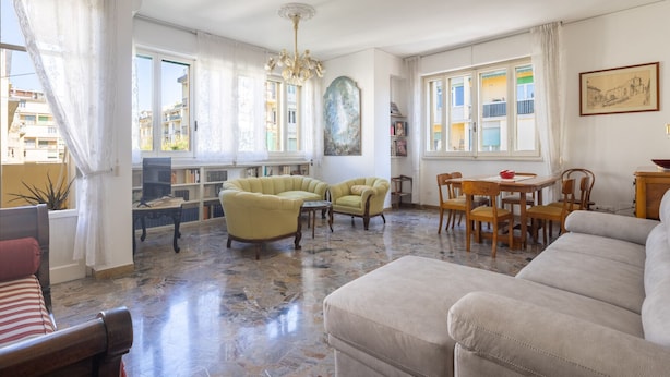 A spacious living room with a large sofa, armchairs, a dining table with chairs, a TV, and a bookshelf. - Gordigiani Apartment (Firenze)