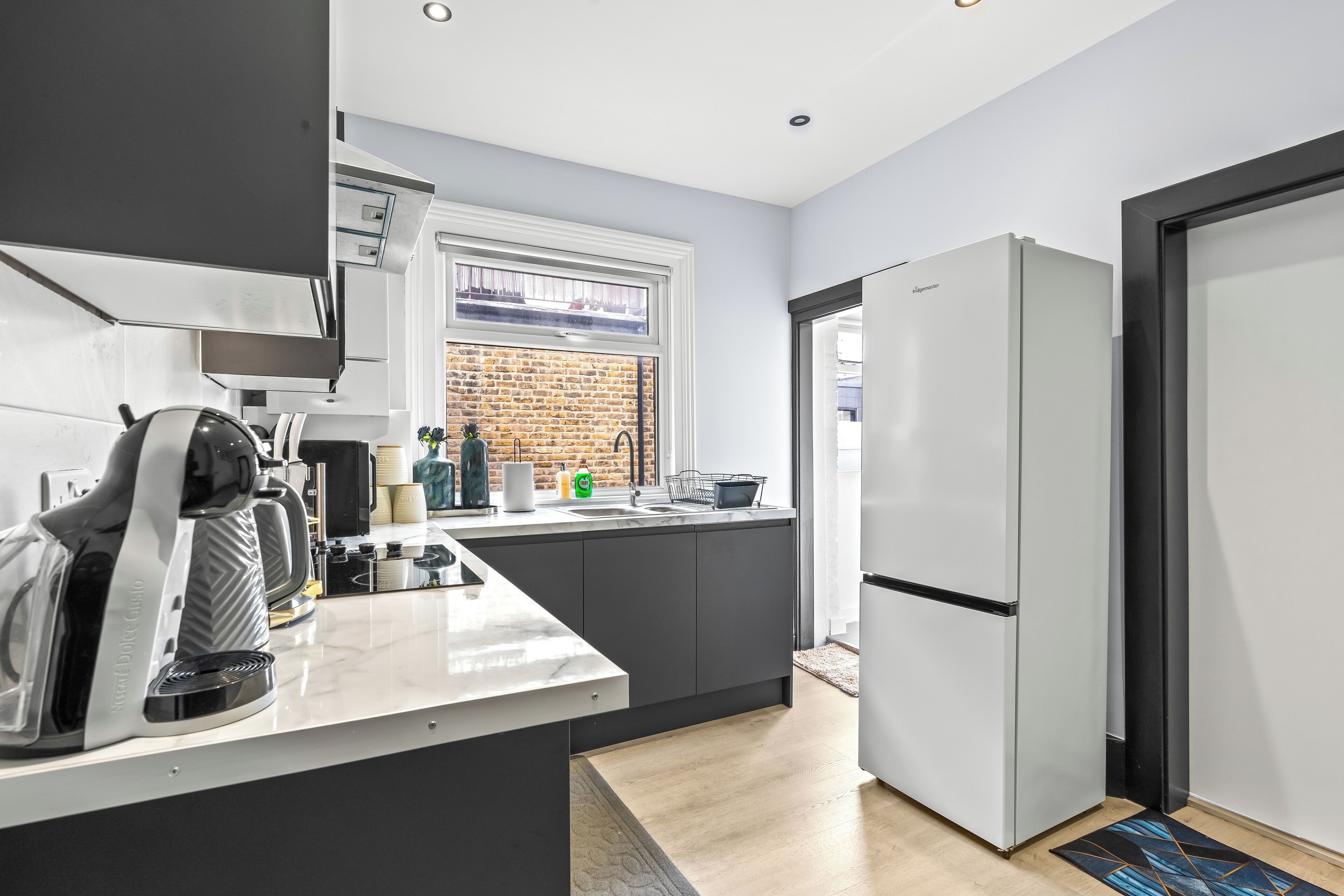 Eine moderne Küche mit Einbauherd, Kaffeemaschine und Kühlschrank.