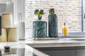 A kitchen counter with two decorative vases with flowers, a white mug, and a bottle of Baylis soap. - Superb 3bed Fulham Palace Retreat (London)