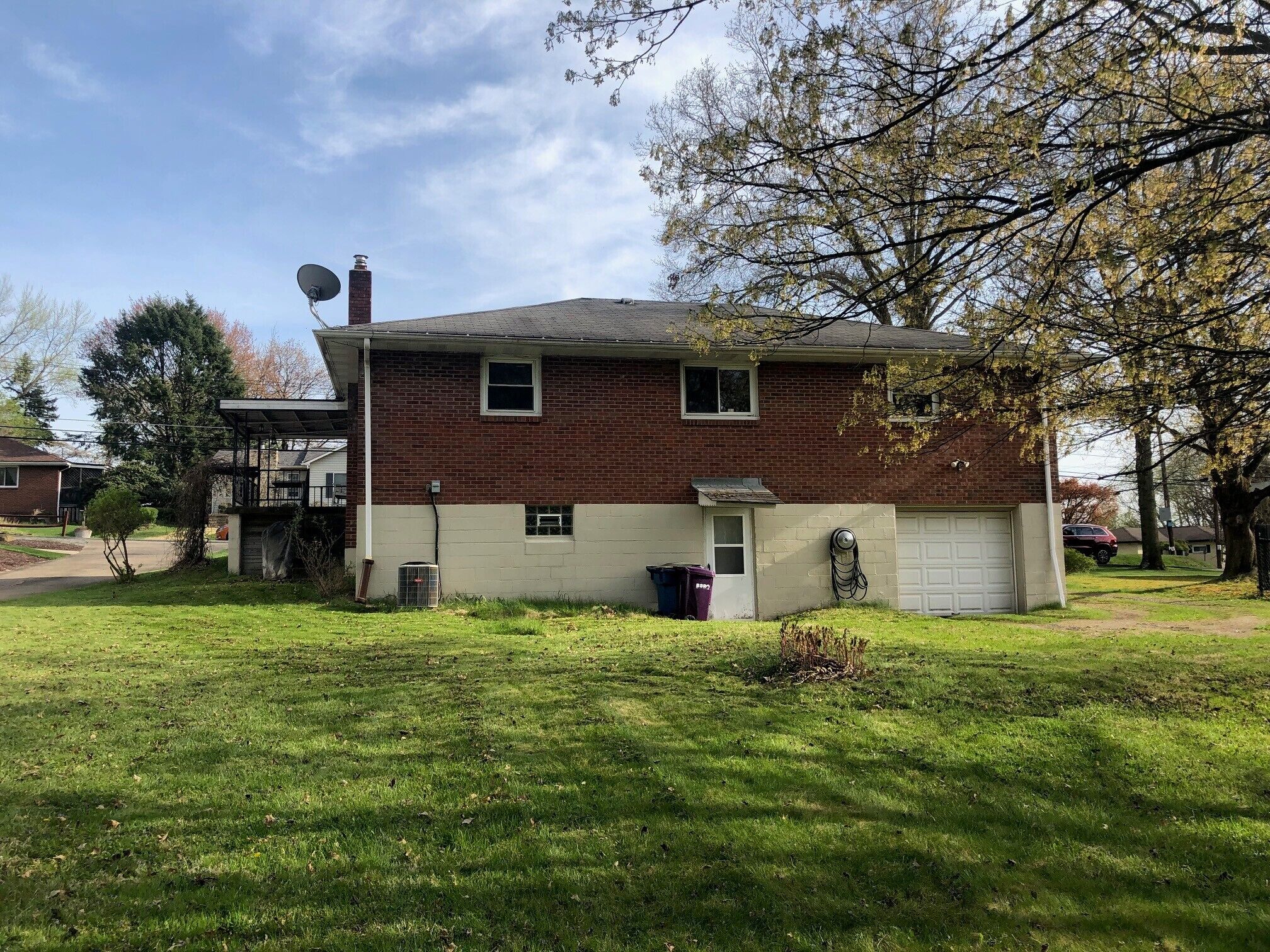 A two-story house with a garage, a satellite dish, and a small front yard.