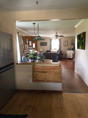 A modern kitchen with a built-in refrigerator, wooden counter, and a dining area with a table and chairs.