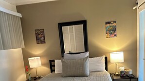 Ein großes Bett mit einer gesteppten Decke, zwei Nachttischlampen, ein Deckenventilator und ein gerahmtes Bild an der Wand.
