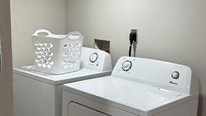 Une buanderie équipée de deux machines à laver à chargement frontal blanches et d’un panier à linge blanc.