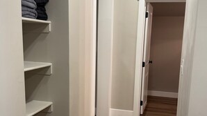 Un couloir étroit avec un plancher en bois, des murs blancs et un placard intégré avec des étagères.