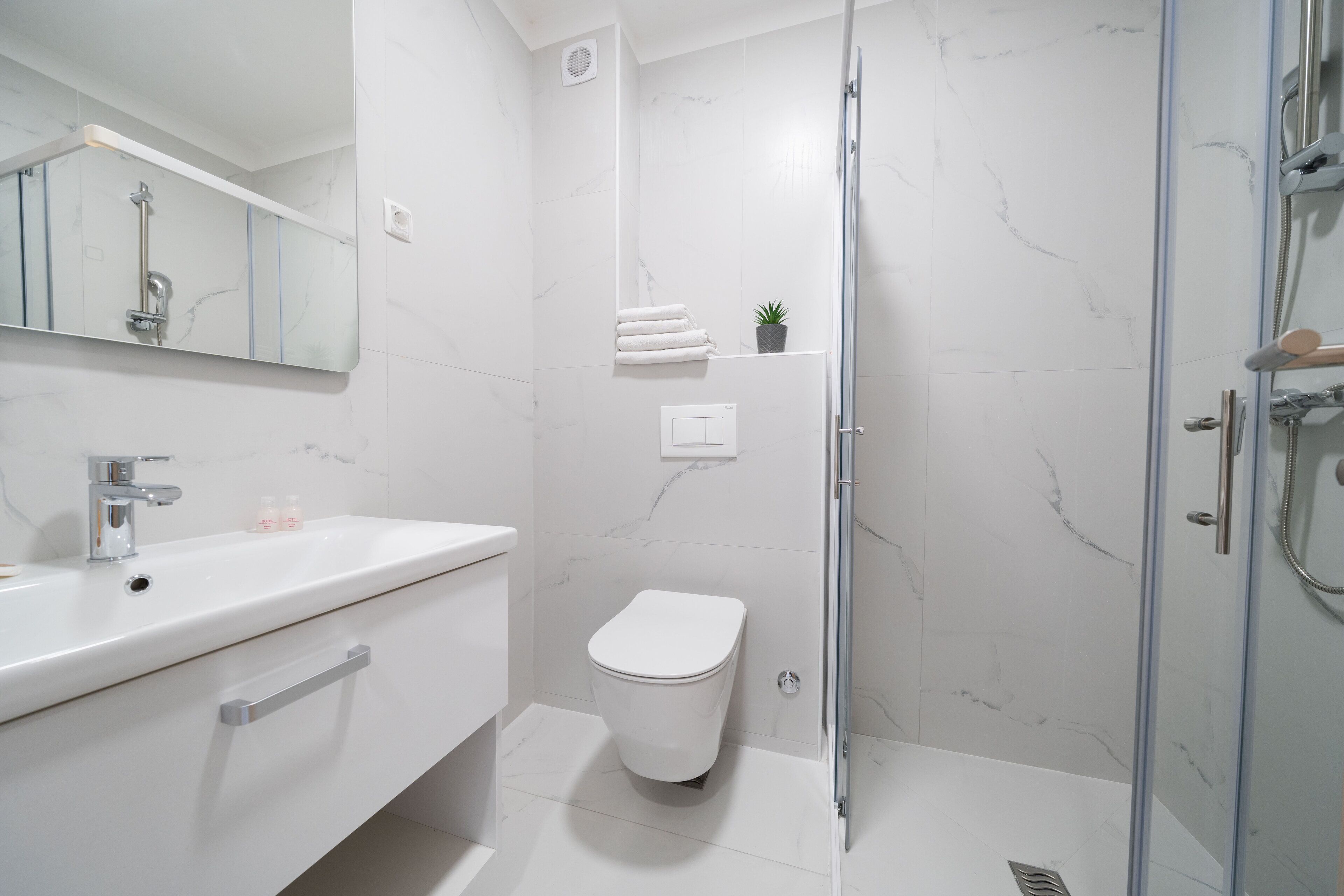Un baño moderno con lavamanos, inodoro y ducha blancos.