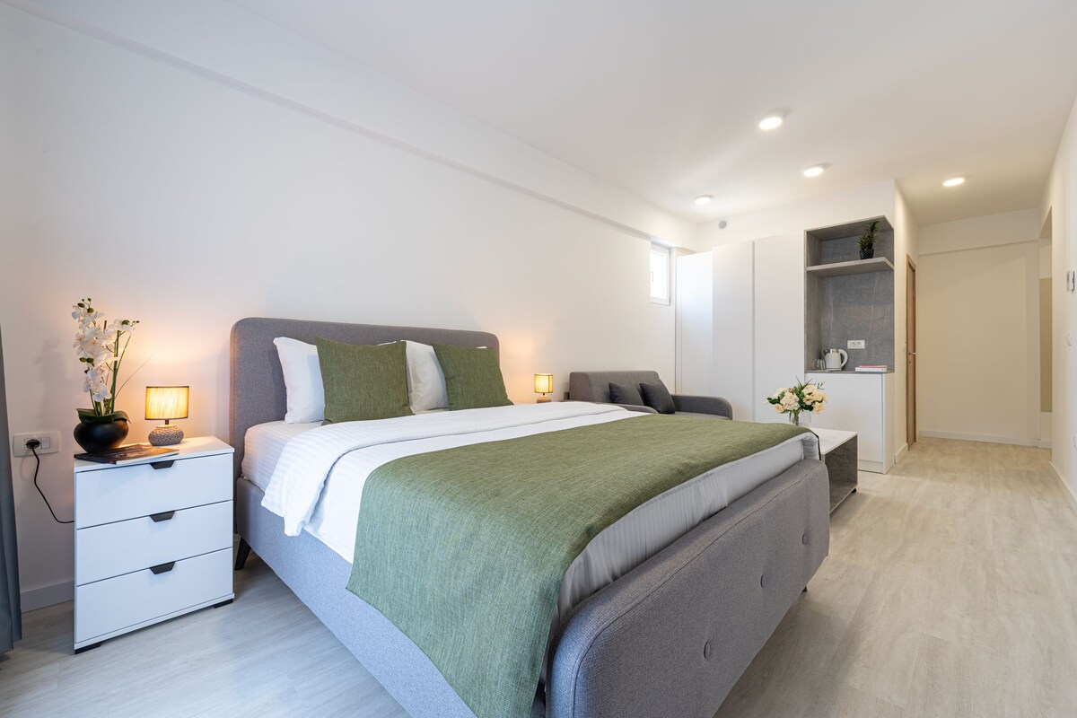 A modern bedroom with a bed, bedside tables, a nightstand, and a built-in shelf with a plant.