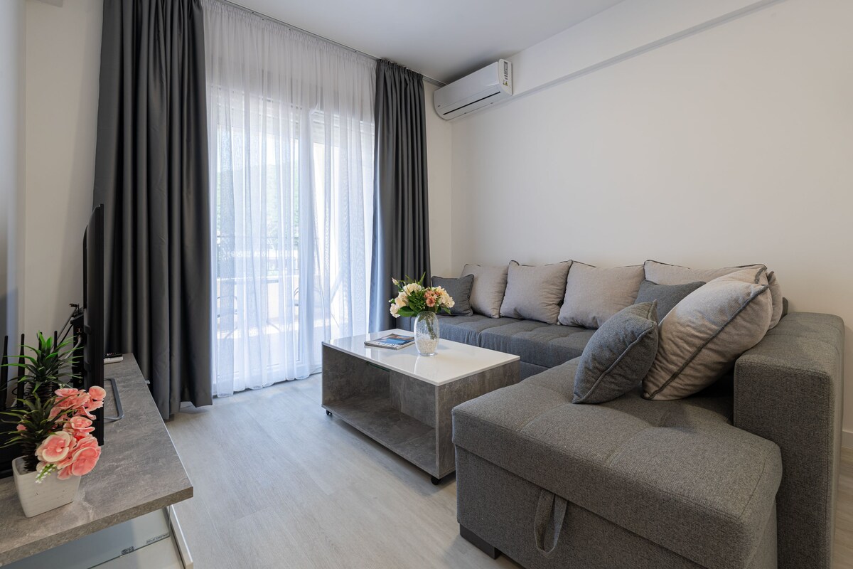 A modern living room with a grey sofa, a coffee table, and a plant.