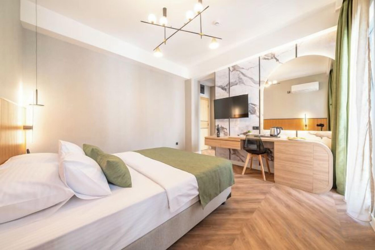 Une chambre d’hôtel moderne équipée d’un lit, d’un bureau et d’un téléviseur à écran plat.