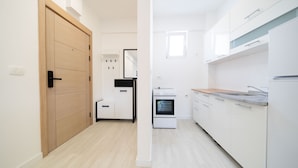 Eine moderne Küche mit weißen Schränken, einem eingebauten Backofen und einer Holztür.