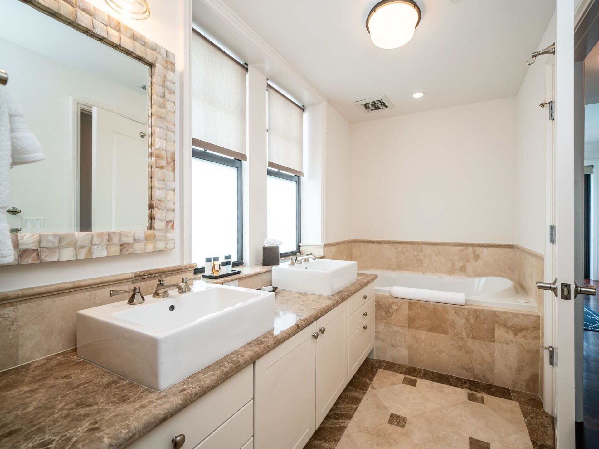 Un baño moderno con dos lavamanos, una bañera y un espejo grande.