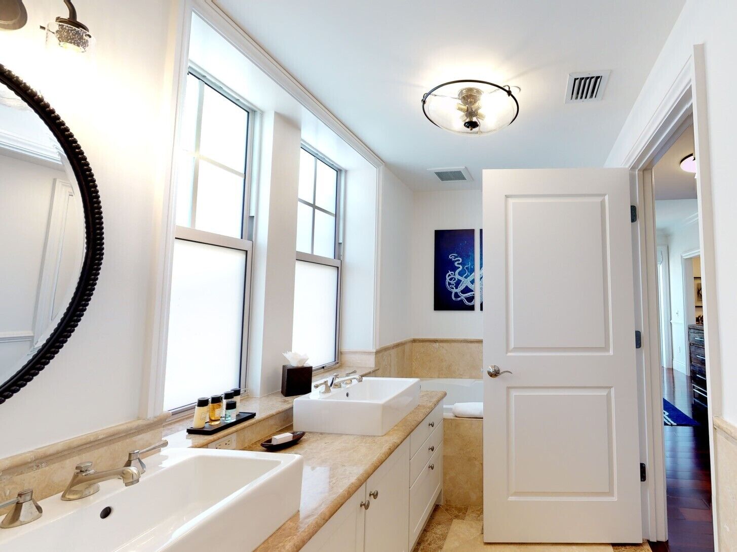 Un bagno moderno con due lavabi, uno specchio grande e una ventola a soffitto.