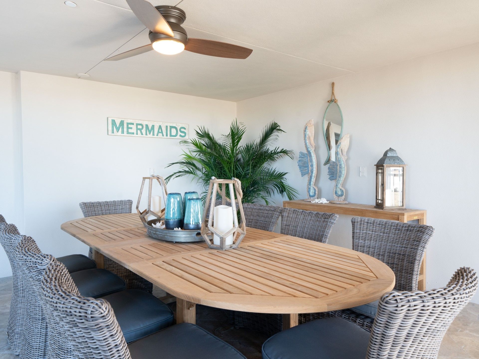 A dining area with a wooden table, wicker chairs, and a ceiling fan.