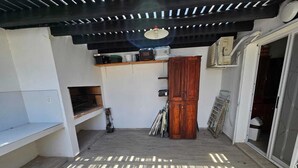 A sunlit room with a wooden cabinet, a shelf with kitchen items, and a sliding door.