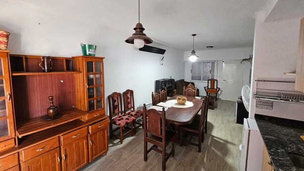 A dining area with wooden furniture, a ceiling fan, and a refrigerator.