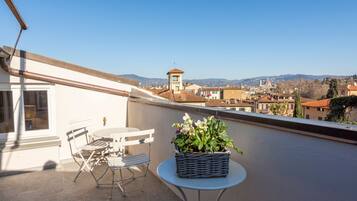 Un balcone con tavolo, sedie e una pianta in vaso.