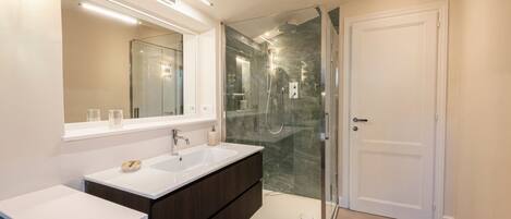 A modern bathroom with a glass-enclosed shower, a large mirror, and a vanity with a dark cabinet.