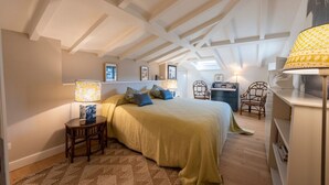 Een slaapkamer met een bed, nachtkastje, lamp, stoel en bureau.