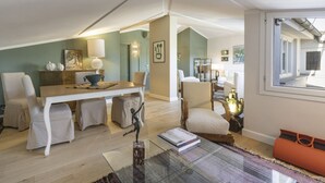 Een ruime woonkamer met een eettafel, stoelen, een bank en een salontafel.